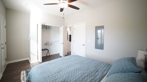 A bedroom with a bed, a ceiling fan, and a walk-in closet.