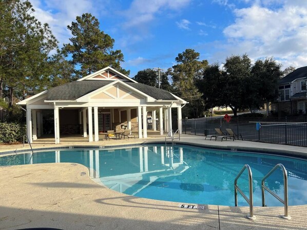 A swimming pool with a covered pavilion, lounge chairs, and a 5 ft depth marker.