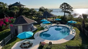 A backyard with a swimming pool, lounge chairs, and a gazebo.