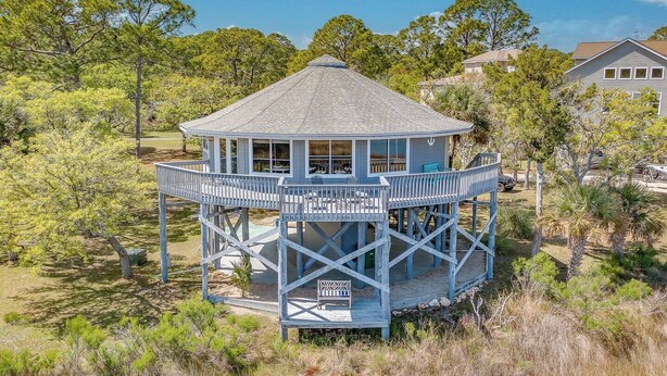 A wooden observation tower with a covered deck, surrounded by trees and a clear sky.