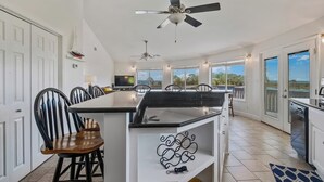 A spacious kitchen with a central island, white cabinetry, and a ceiling fan.
