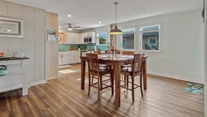 A modern kitchen with white cabinets, a dining table with chairs, and a ceiling fan. - For the Birds- relax on the lagoon! (Alligator Point)