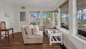 A room with a white ceiling fan, a beige sofa with cushions, a wooden chair, and a small white table. - For the Birds- relax on the lagoon! (Alligator Point)