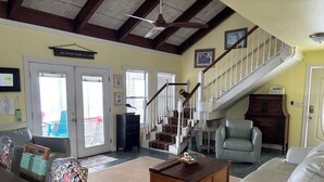 A spacious living room with a high ceiling, a staircase, and a view of the outside. - Lighthouse- enjoy the water, bask in the view (Alligator Point)
