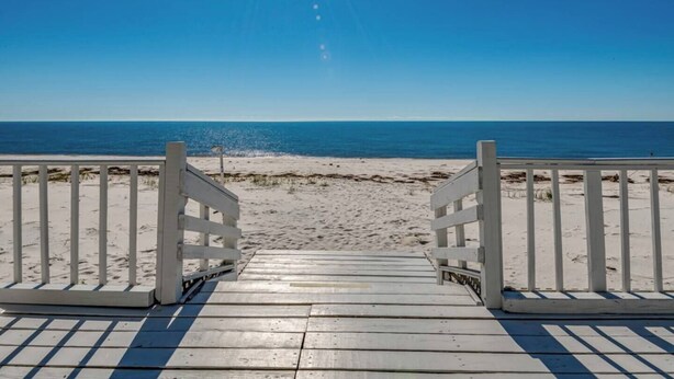 A wooden boardwalk leading to a beach with a clear view of the ocean. - Lighthouse- enjoy the water, bask in the view (Alligator Point)