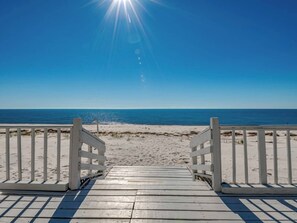 Une promenade en bois qui mène à une plage d’où l’on a une vue dégagée sur l’océan.