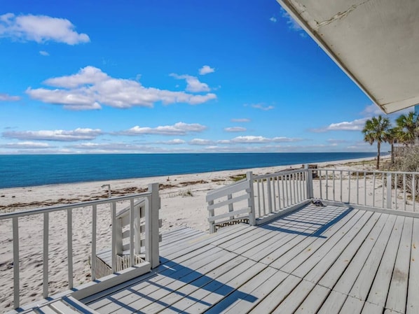Une terrasse en bois avec une rambarde donnant sur une plage.