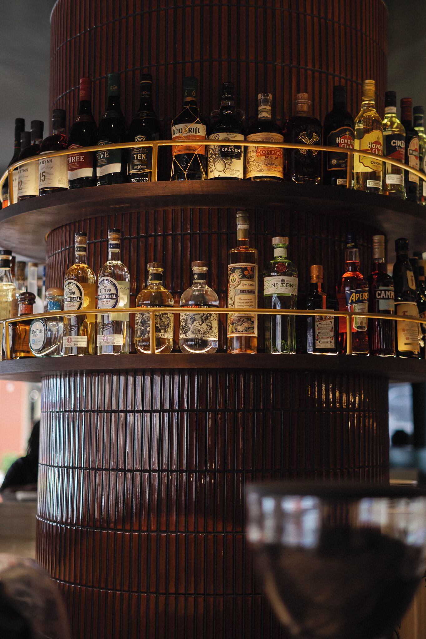 Un bar de varios niveles con diversas botellas de licor.