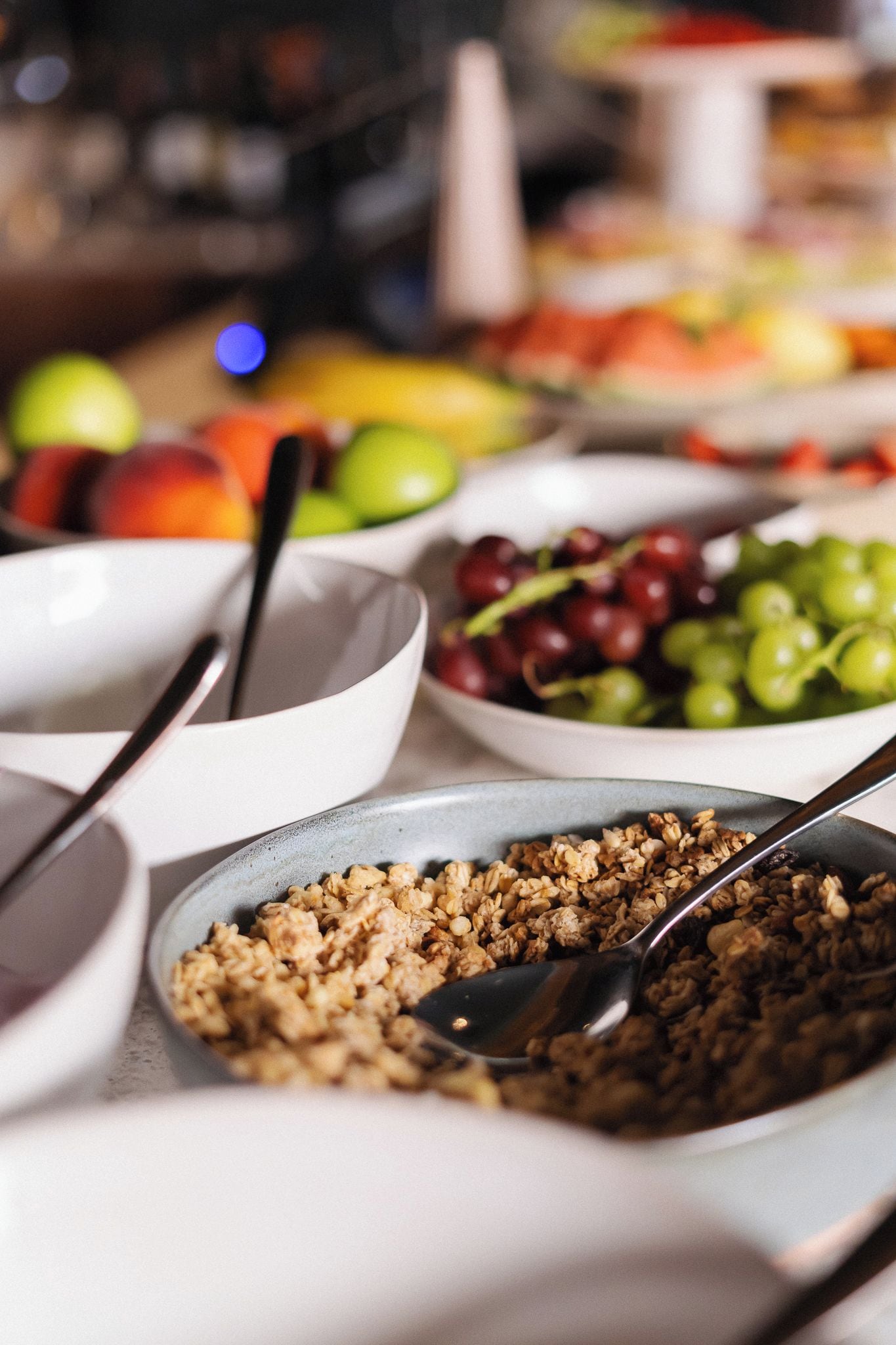 A table with bowls of food, including fruits and granola.