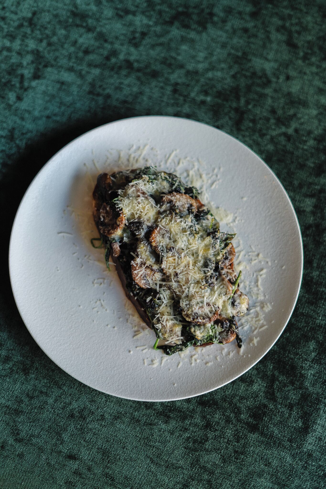 A white plate with a food item on a textured green surface.