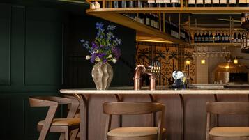 A bar area with wooden chairs, a bar counter, and a wine rack with bottles.