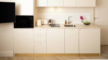 A modern kitchen with white cabinetry, a built-in microwave, a toaster, a sink, and a small vase with flowers.