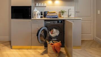 A compact kitchen with a washing machine, a microwave, and a sink.