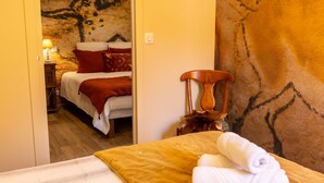 A bedroom with a bed, a chair, and a wall with a textured pattern. - Chambre d'hôtes Le Rucher des Combes - Lascaux room (Fleurac)