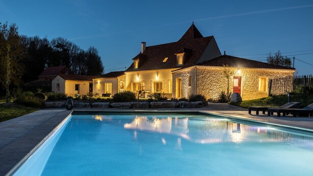 A large house with a swimming pool, stone exterior, and warm lighting. - Chambre d'hôtes Le Rucher des Combes - Lascaux room (Fleurac)