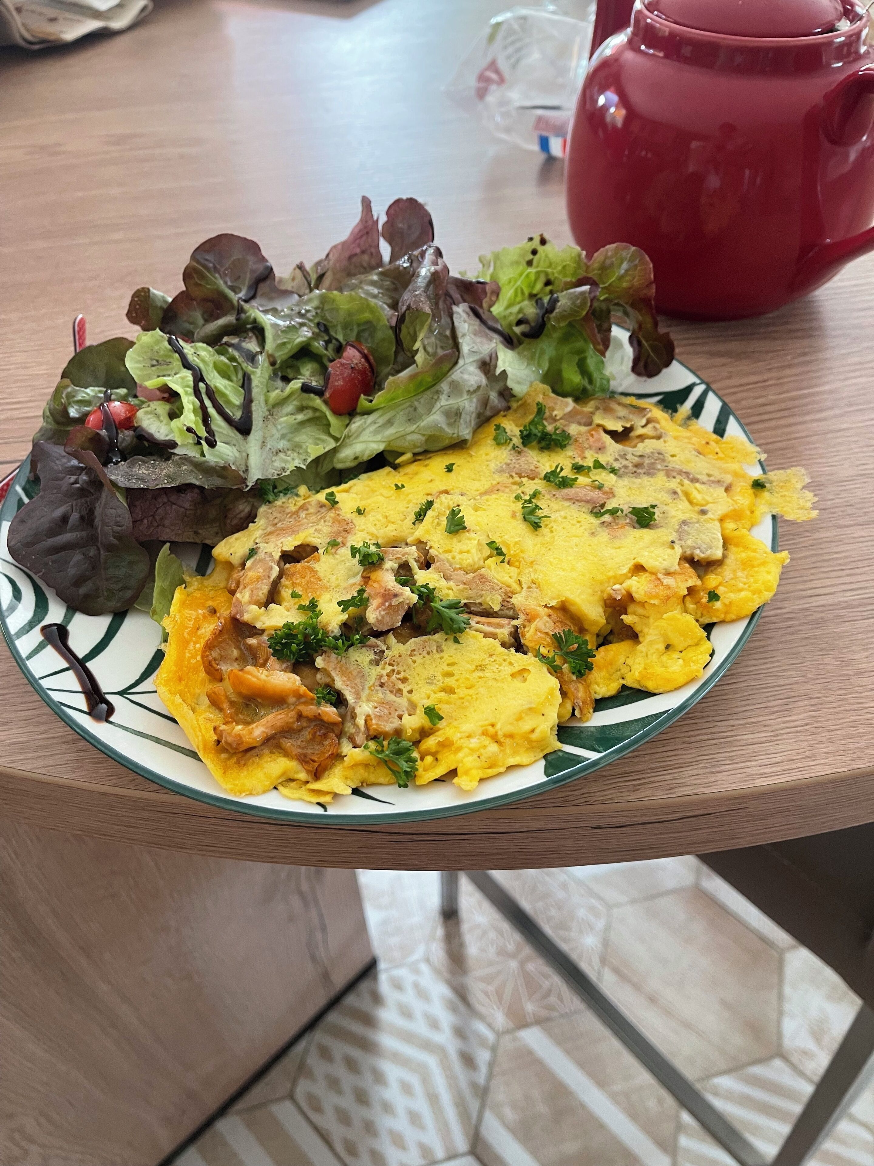 A plate with scrambled eggs, mushrooms, and parsley, alongside a mixed green salad with cherry tomatoes.