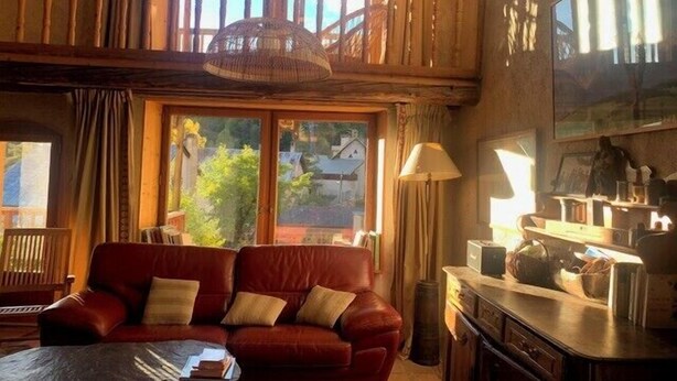 A cozy living room with a red leather sofa, a dining table, and a balcony with wooden railings. - Large house near the slopes, La Salle-les-Alpes (La Salle-les-Alpes)