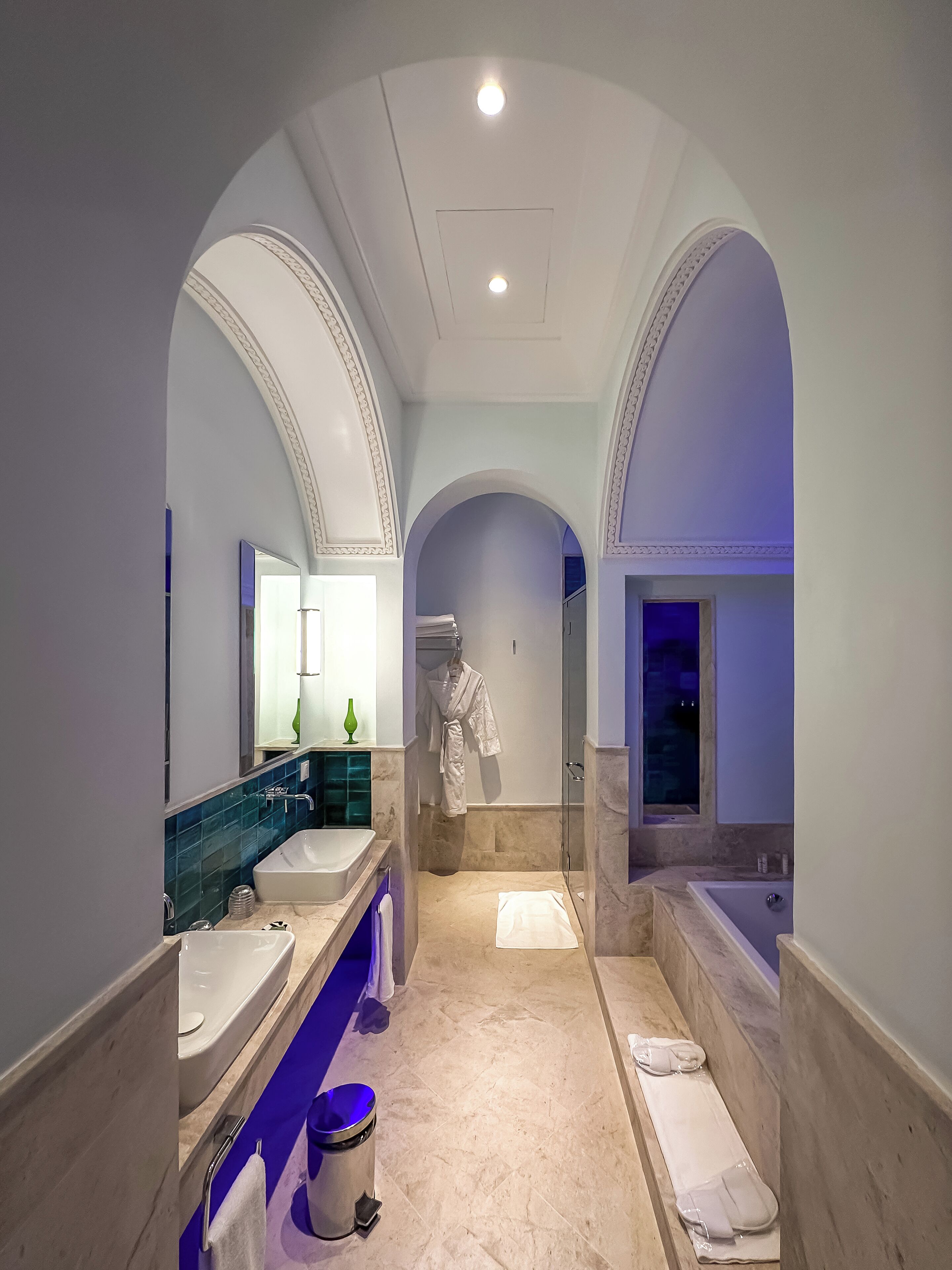 Un baño moderno con un espejo grande, dos lavamanos, una bañera y una ducha.