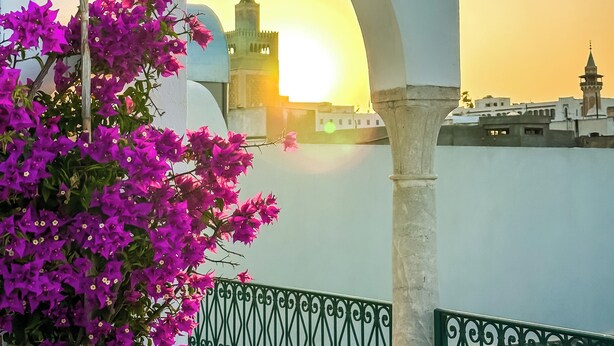 Un balcón con vistas a una mezquita y al atardecer.