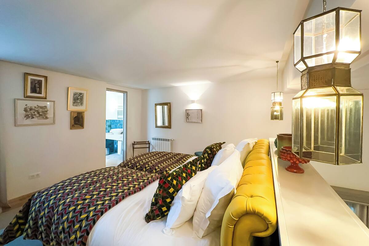 A bedroom with a bed, a yellow headboard, and a bedside table with a lamp.