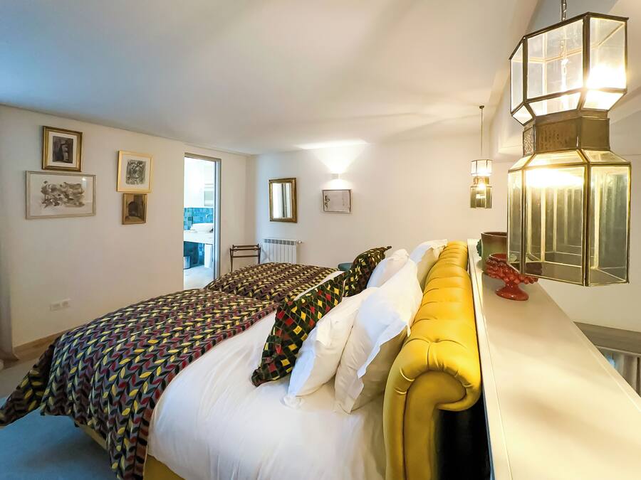 A bedroom with a bed, a yellow headboard, and a bedside table with a lamp.