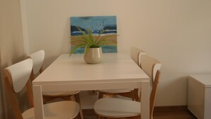Ein Essbereich mit einem weißen Tisch, vier Holzstühlen und einem Blumentopf.