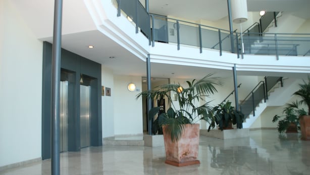 Un'ampia hall con pavimento lucido, una scala e piante in vaso.