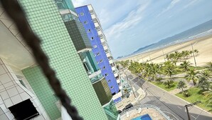 A high-rise building with a pool area, a beach view, and a clear sky. - Foot in the sand at Maracanã beach II (Praia Grande)