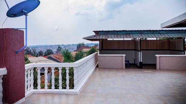 A balcony with a satellite dish, a white railing, and a view of the cityscape. - Prestige villa palace (Kigali)