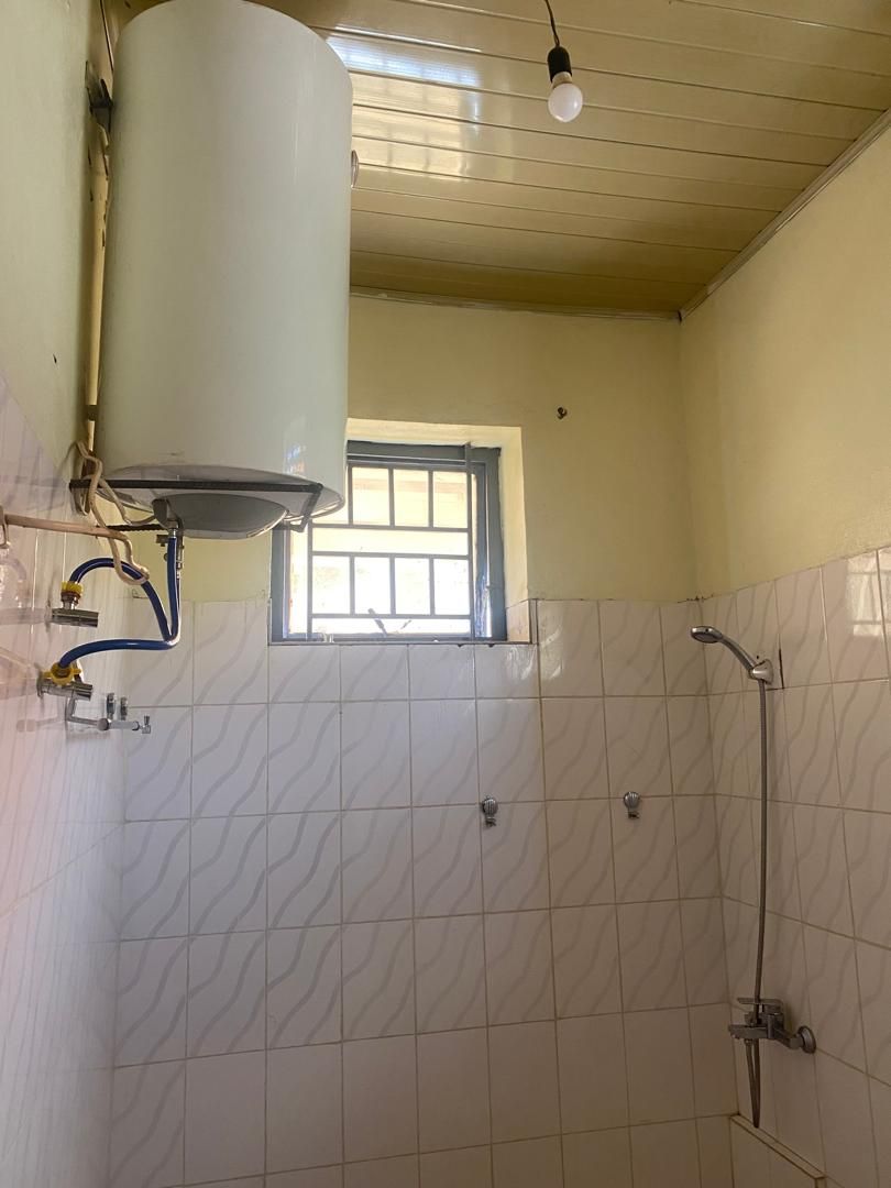A bathroom with a shower, a window, and a water heater.
