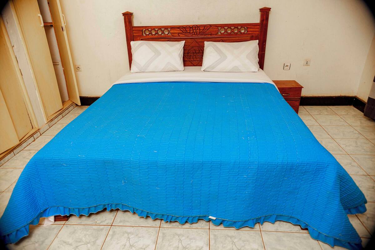 Un lit avec une couvre-lit bleue, une tête de lit en bois et deux oreillers.