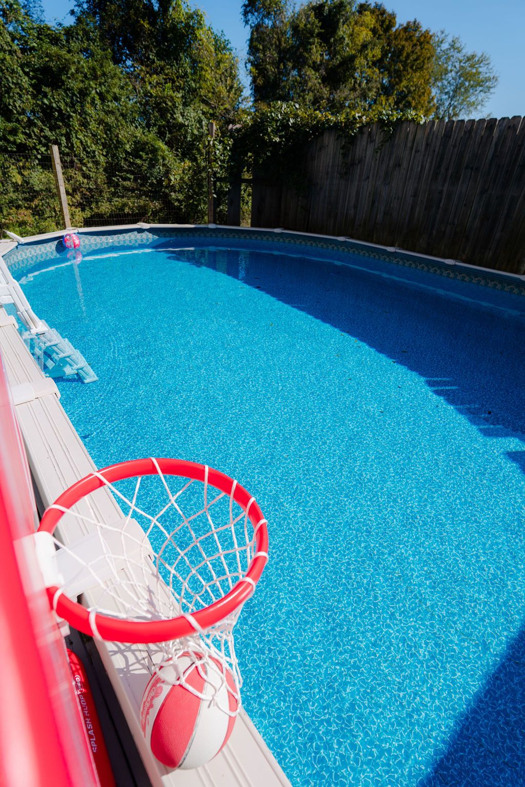 A swimming pool with a basketball hoop.