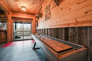 A shuffleboard table in a wooden room with a balcony. - Buckets Lodge | Sleeps 28, Theater & Basketball (Logan)