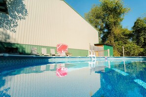 Une piscine avec des chaises longues et un bâtiment en arrière-plan.