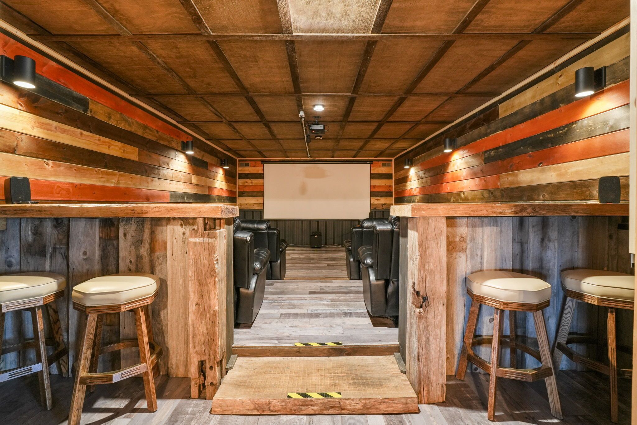 Eine Reihe von Barhocker, am Ende einer Holzgasse ein Projektionsschirm.