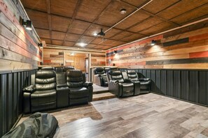 A room with wooden panel walls, a ceiling fan, and multiple leather recliners. - Buckets Lodge | Sleeps 28, Theater & Basketball (Logan)