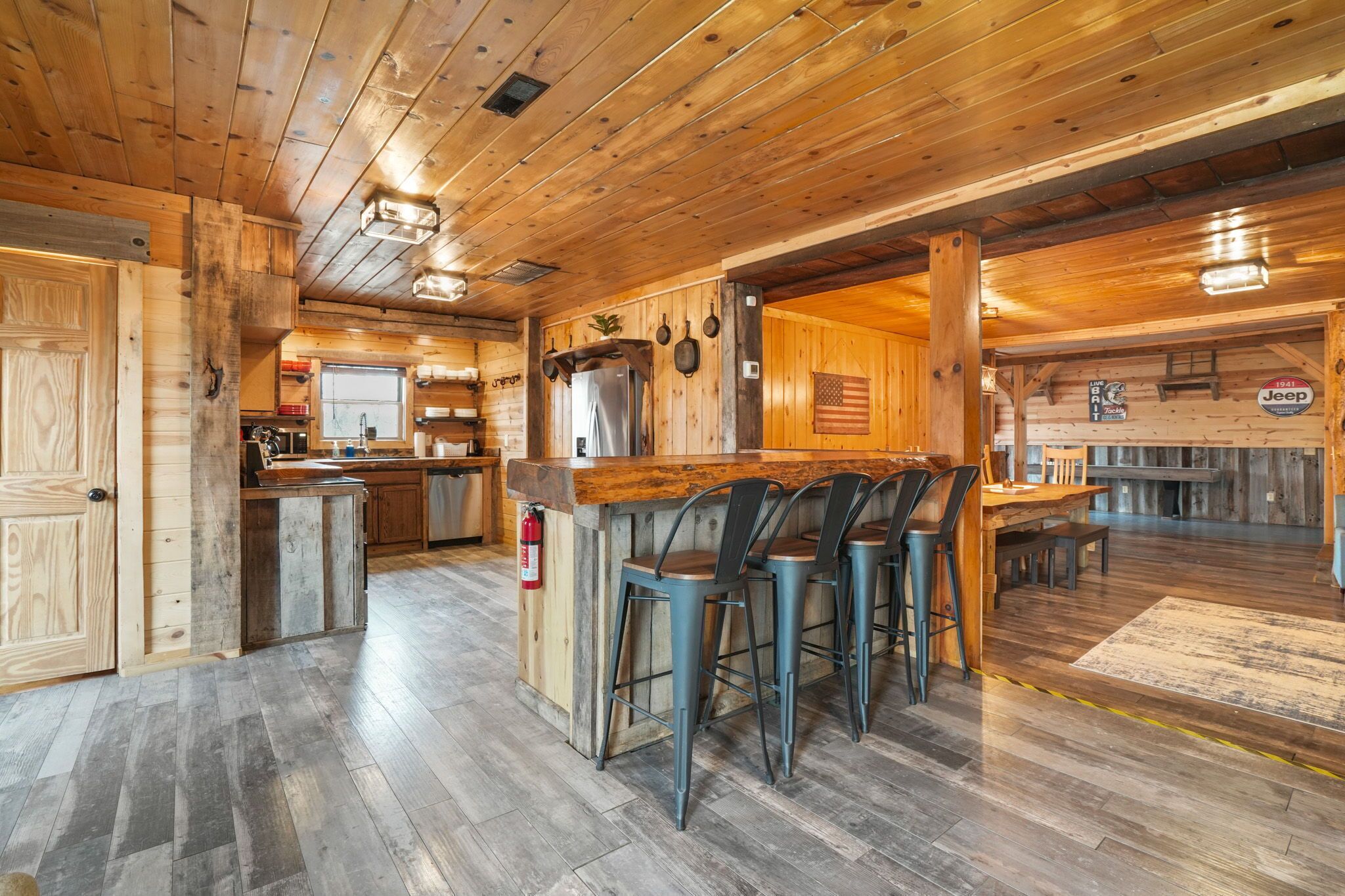 A rustic wooden interior with a bar area, kitchen, and seating space.