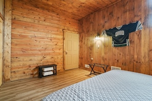 A wooden-paneled room with a bed, a bench, and a door. - Buckets Lodge | Sleeps 28, Theater & Basketball (Logan)