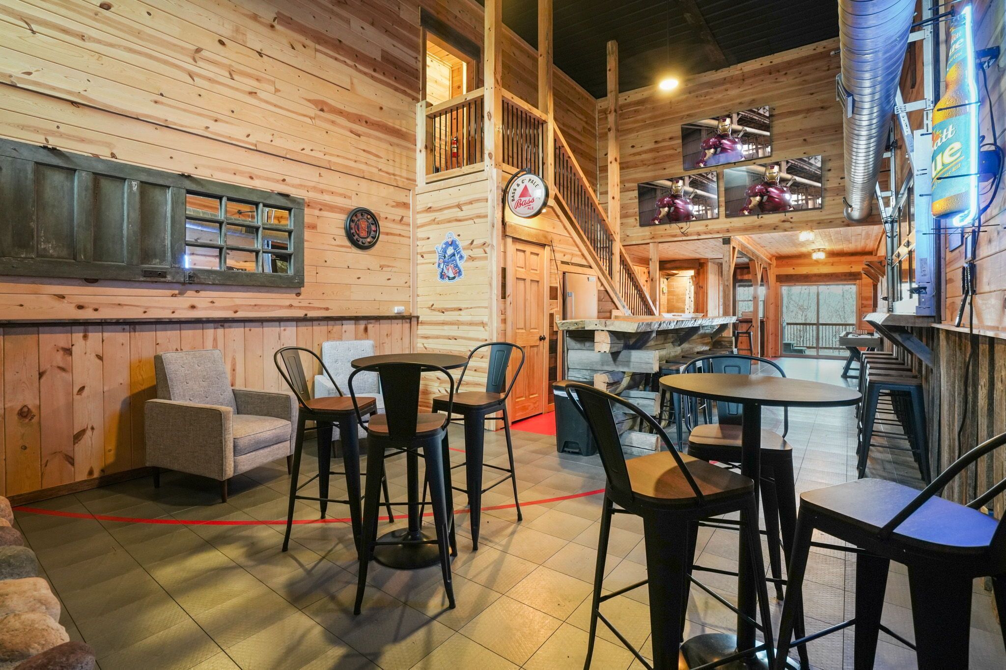 A wooden interior with a staircase, tables, and chairs.