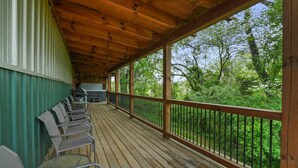 Una terrazza esterna coperta con pavimento in legno, sedie in metallo e una griglia.