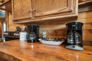 A kitchen counter with a coffee maker, a coffee pot, and a bowl of coffee pods. - Buckets Lodge | Sleeps 28, Theater & Basketball (Logan)