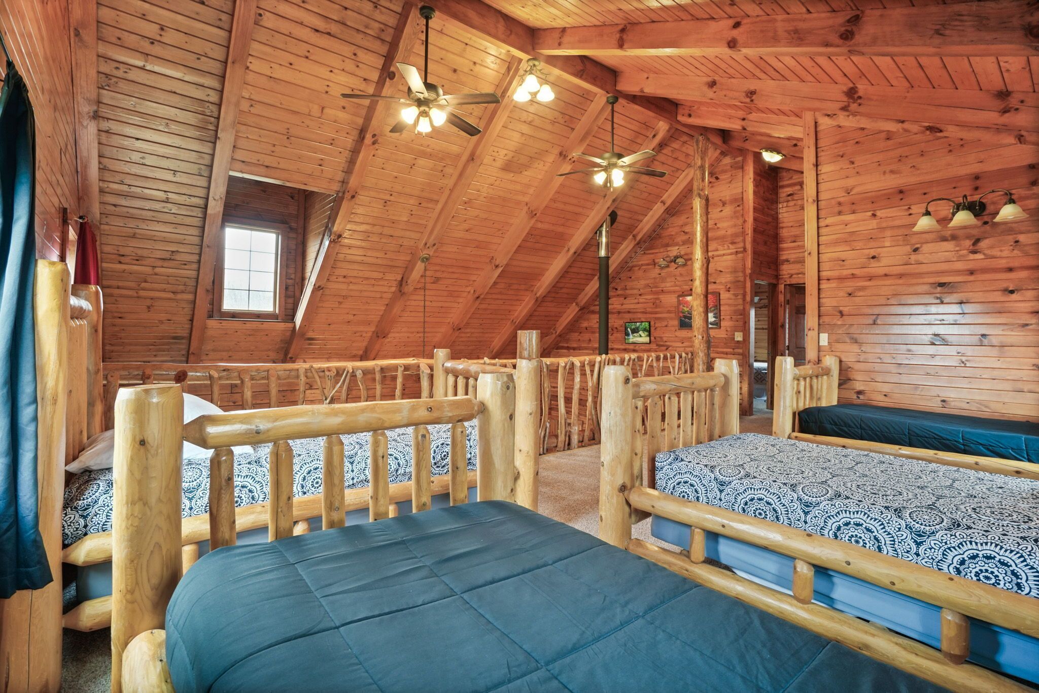Une cabane en bois avec deux lits, un plafond en pente et une petite fenêtre.