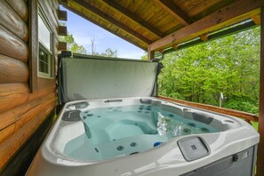 Un jacuzzi en una cabaña de madera con vistas a un bosque.