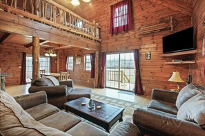 Une cabane en bois spacieuse, dotée d’un balcon, d’un grand téléviseur et d’un coin salon confortable.