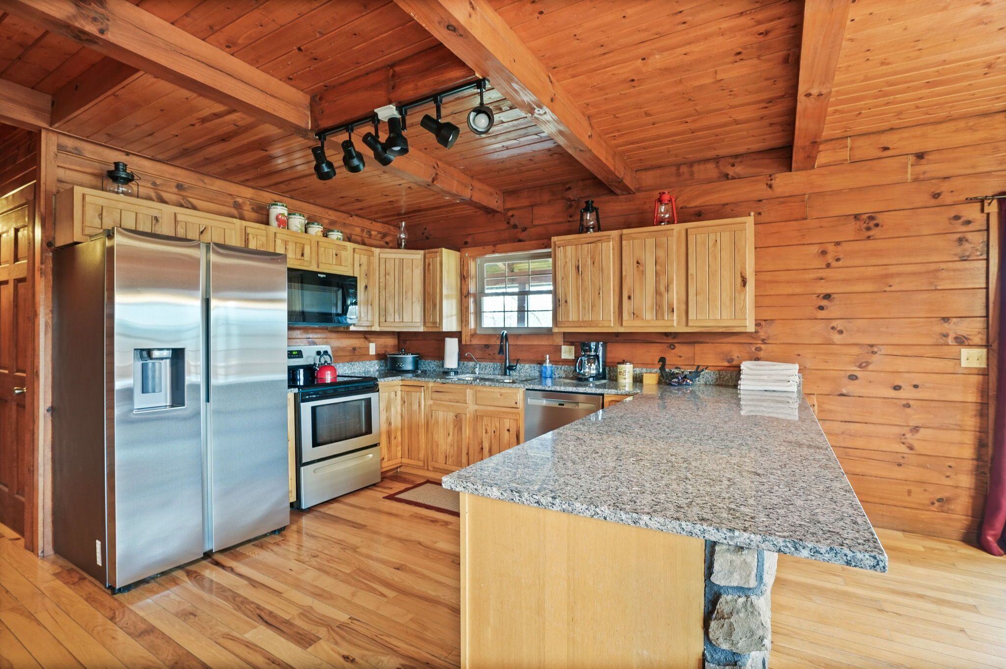 Una cocina moderna con armarios de madera, encimeras de granito, electrodomésticos de acero inoxidable y una isla de piedra.
