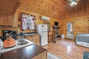 A wooden cabin interior with a kitchen, a dining area, and a bedroom. - Hide-A-Way Tiny House | Hocking Hills, Hot Tub (Logan)