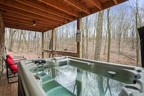 A hot tub in a wooden cabin with a view of a forest.