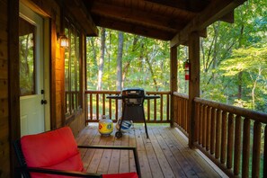 A wooden deck with a grill, a chair, and a gas canister.