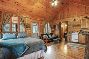 A wooden cabin with a bed, sofa, and kitchenette.