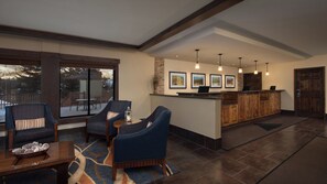 A spacious lobby with a reception desk, seating area with chairs, and a large window overlooking a deck. - Beautiful Villa At Marriott Evergreen Sleeps 8 (Vail)